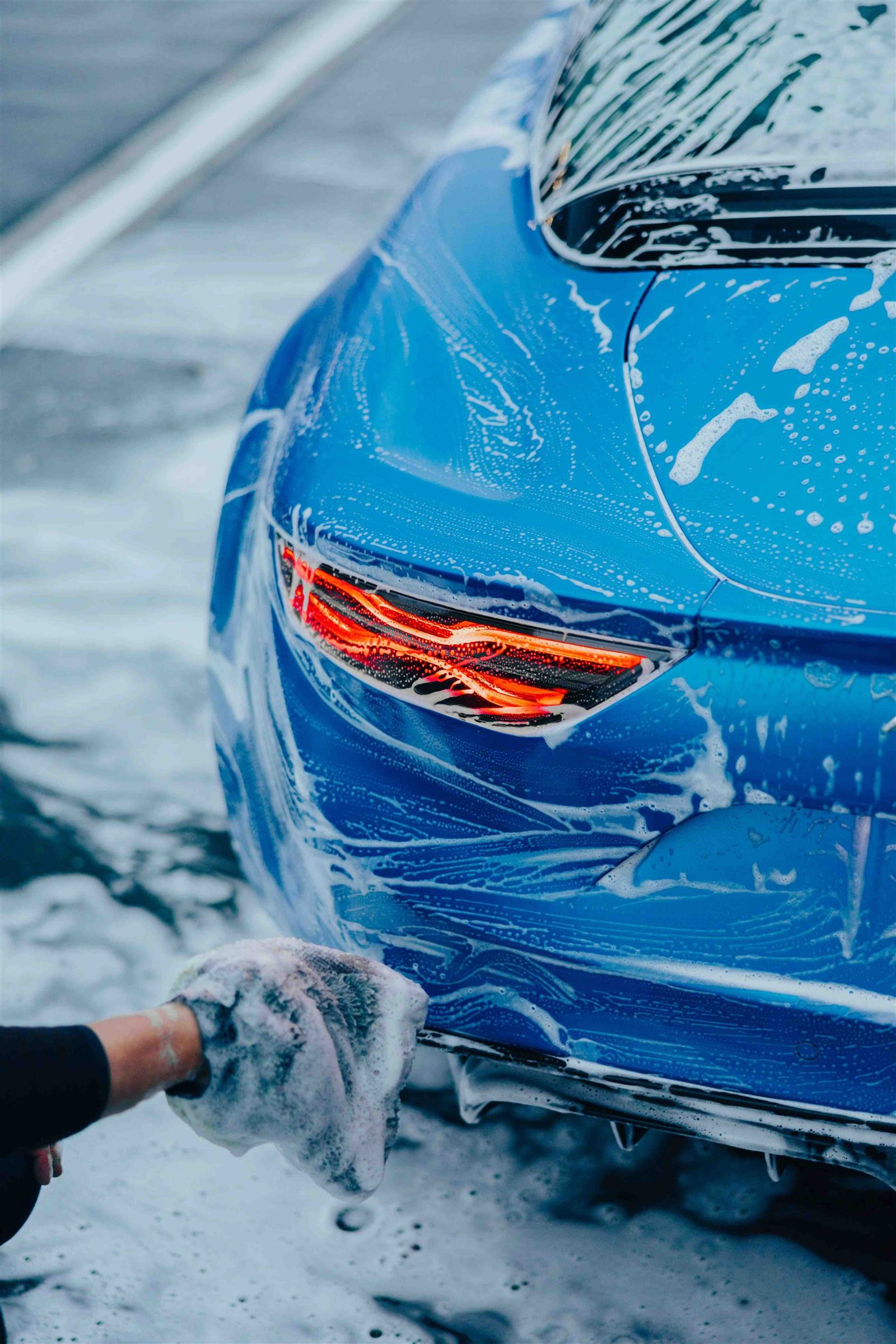 A blue car being washed by hand at the customer’s location